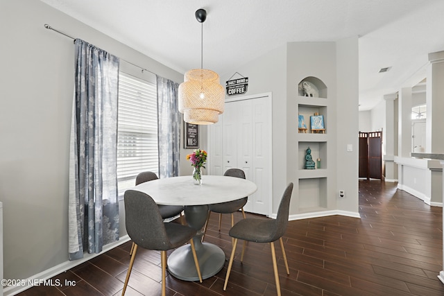 dining space featuring built in features, wood finish floors, ornate columns, and baseboards