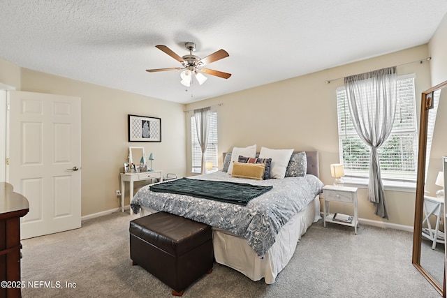 carpeted bedroom with a textured ceiling, ceiling fan, multiple windows, and baseboards