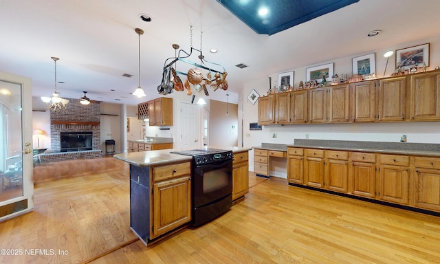 kitchen featuring brown cabinetry, open floor plan, black / electric stove, light wood-type flooring, and a brick fireplace