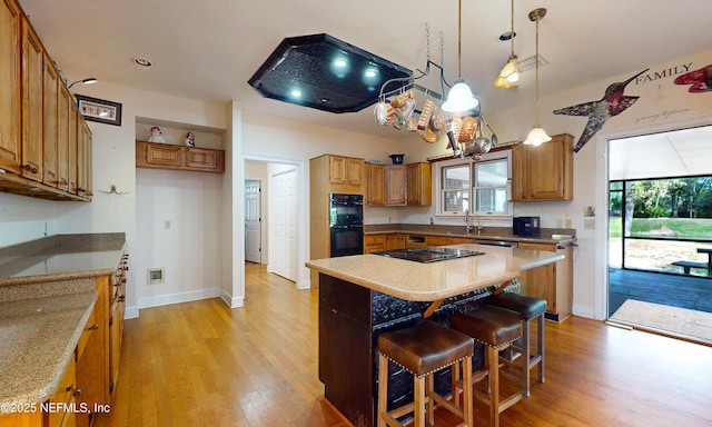 kitchen featuring black appliances, brown cabinetry, light wood-type flooring, and a sink