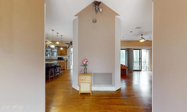 hall featuring a sink, wood finished floors, visible vents, and baseboards