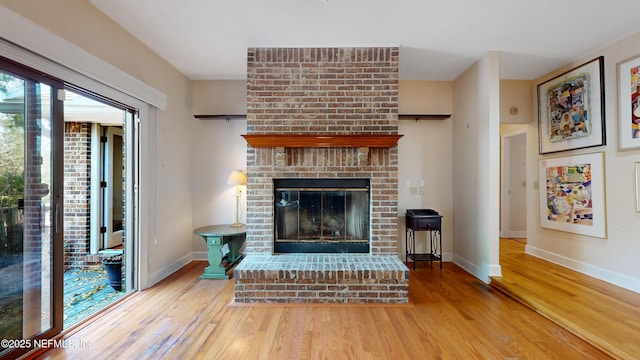 living room featuring a fireplace, baseboards, and wood finished floors