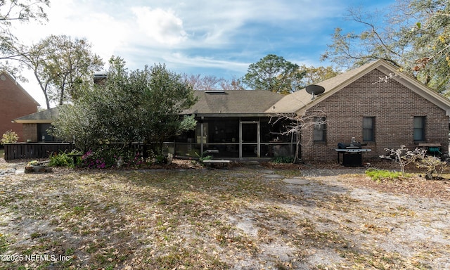 rear view of property featuring brick siding and a sunroom