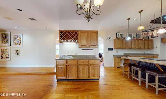 kitchen with pendant lighting, light wood finished floors, visible vents, an inviting chandelier, and baseboards