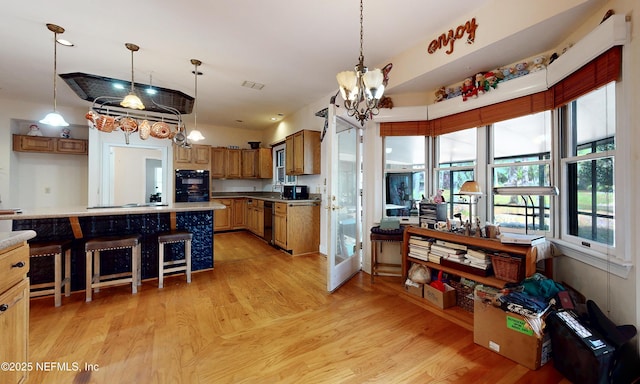 kitchen with dobule oven black, light wood-style flooring, brown cabinetry, and decorative light fixtures