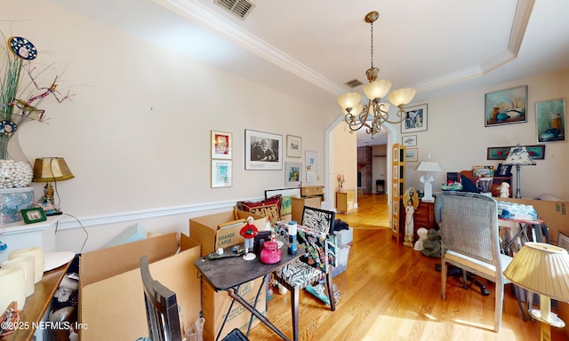 dining area with a tray ceiling, visible vents, light wood finished floors, and an inviting chandelier