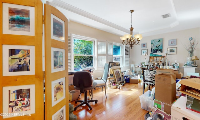 office featuring a raised ceiling, visible vents, an inviting chandelier, light wood-style floors, and ornamental molding