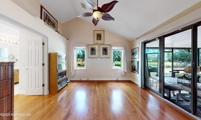 interior space featuring baseboards, visible vents, a ceiling fan, lofted ceiling, and light wood-style flooring