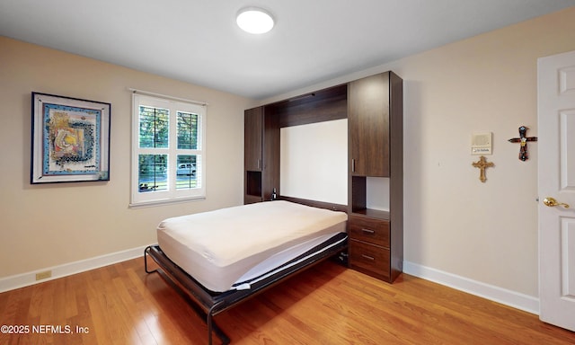 bedroom featuring light wood finished floors and baseboards