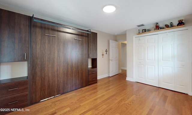 unfurnished bedroom with light wood-style flooring, a closet, visible vents, and baseboards