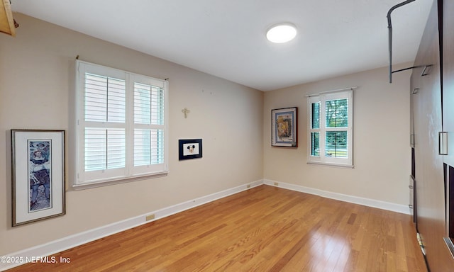 unfurnished room featuring light wood-style floors, visible vents, and baseboards