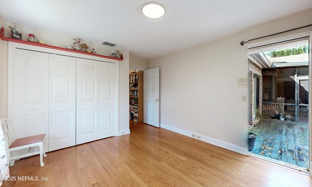 unfurnished bedroom featuring light wood-type flooring, a closet, visible vents, and baseboards