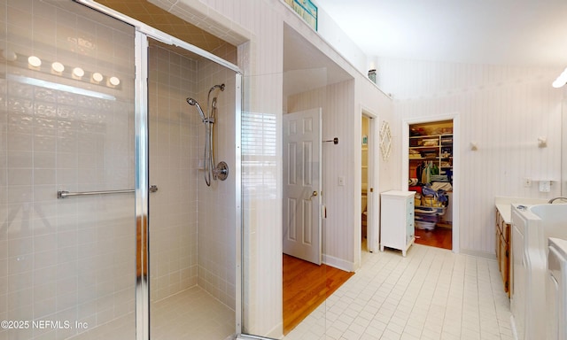 bathroom with a stall shower, lofted ceiling, tile patterned floors, a spacious closet, and vanity