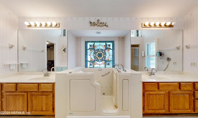 full bath featuring a jetted tub, a shower stall, two vanities, and a sink