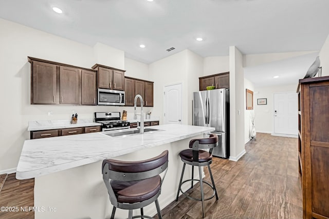 kitchen with dark brown cabinetry, dark wood-style flooring, a sink, visible vents, and appliances with stainless steel finishes