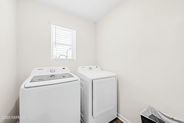 washroom featuring laundry area, baseboards, and separate washer and dryer