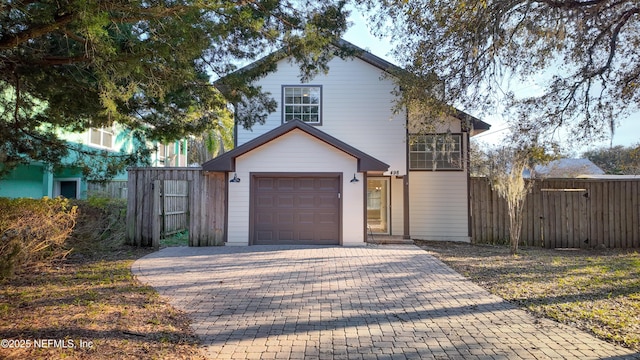 view of front facade with a garage, decorative driveway, and fence