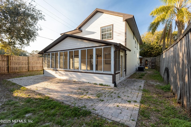 rear view of property featuring a patio area, a fenced backyard, and a sunroom