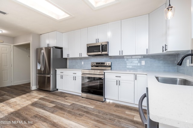 kitchen featuring white cabinetry, stainless steel appliances, a sink, and light countertops