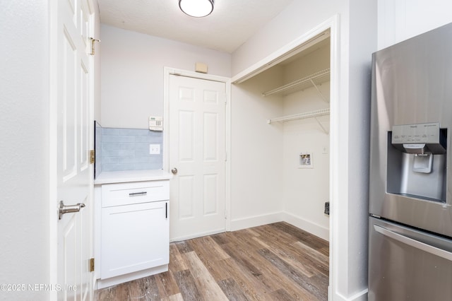 clothes washing area with washer hookup, baseboards, and wood finished floors