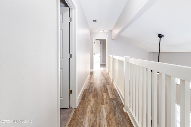 hall featuring visible vents, lofted ceiling with beams, baseboards, and wood finished floors