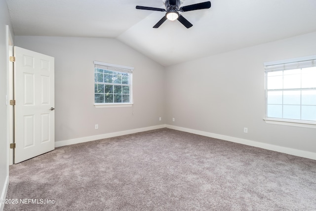 carpeted spare room with vaulted ceiling, ceiling fan, and baseboards