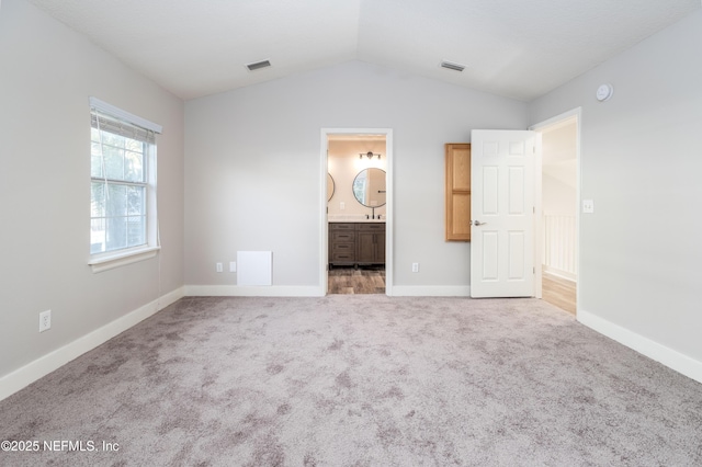 unfurnished bedroom with carpet floors, baseboards, visible vents, and lofted ceiling