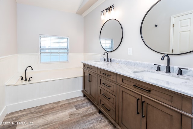 bathroom featuring a wainscoted wall, a sink, and wood finished floors