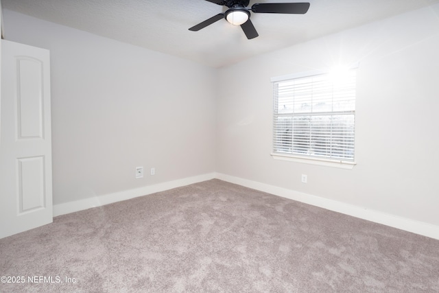 empty room with carpet floors, a ceiling fan, and baseboards