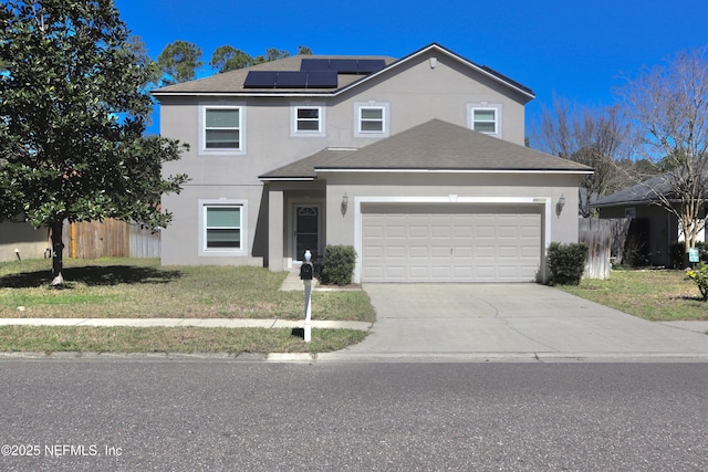 traditional home featuring an attached garage, fence, driveway, roof mounted solar panels, and stucco siding