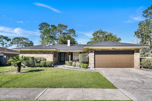 view of front of house with brick siding, a front lawn, concrete driveway, a chimney, and an attached garage