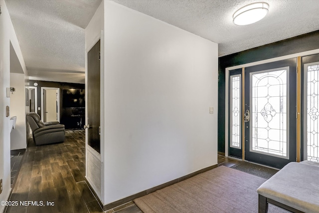 foyer with a textured ceiling, baseboards, and dark wood-style flooring