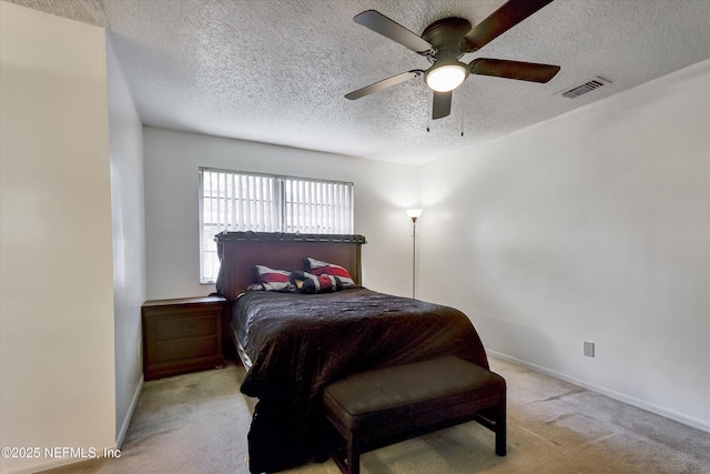 bedroom with visible vents, light carpet, a textured ceiling, baseboards, and ceiling fan