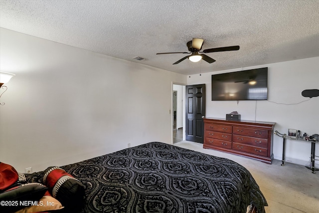 bedroom featuring visible vents, light carpet, a textured ceiling, and ceiling fan