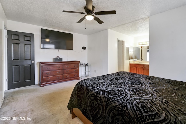 bedroom featuring light colored carpet, ceiling fan, ensuite bathroom, and a textured ceiling