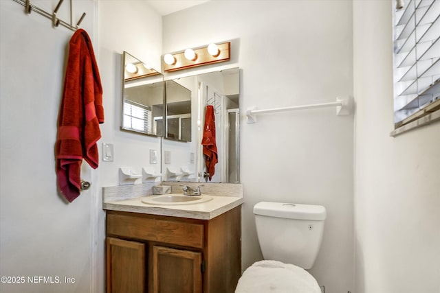 full bathroom featuring a shower with door, toilet, and vanity