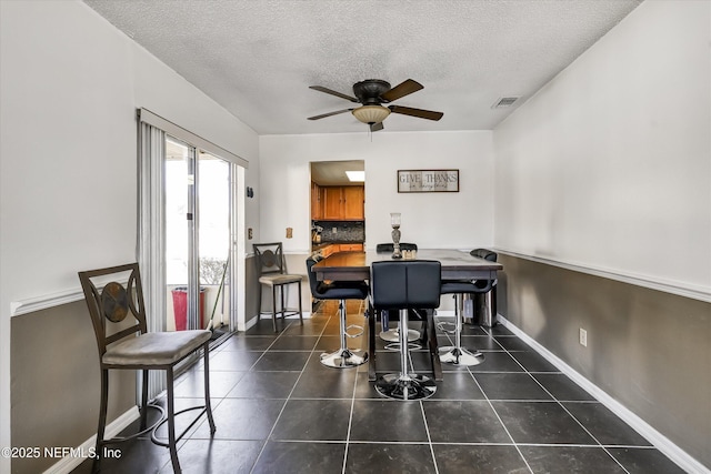 dining space with tile patterned flooring, a textured ceiling, and baseboards