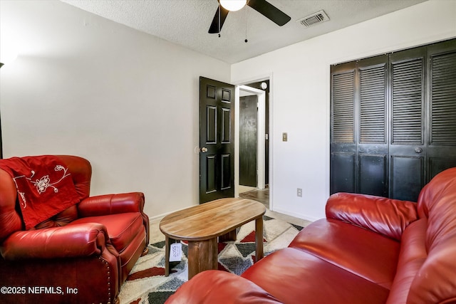 carpeted living room featuring a textured ceiling, baseboards, visible vents, and ceiling fan