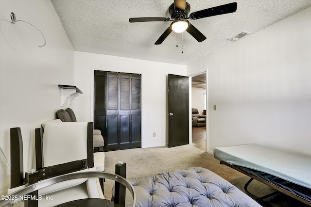 bedroom featuring visible vents, carpet floors, a textured ceiling, and ceiling fan