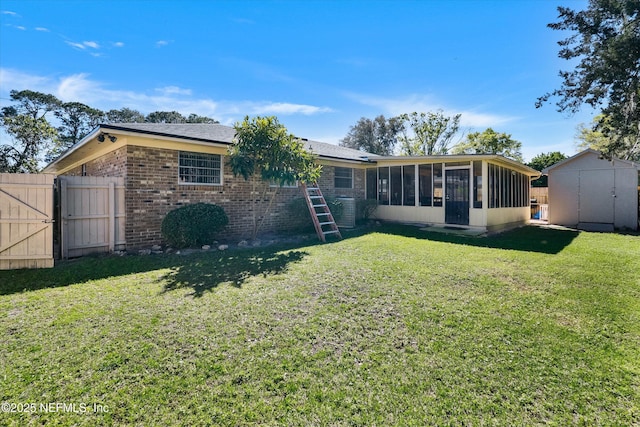 rear view of property with a lawn, a storage shed, an outdoor structure, a sunroom, and a gate