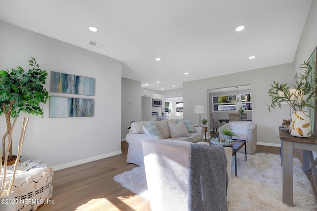 living area with light wood-style flooring, visible vents, baseboards, and recessed lighting