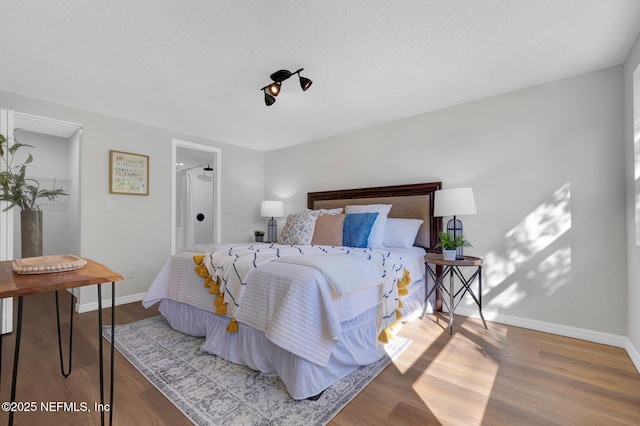 bedroom featuring a textured ceiling, wood finished floors, and baseboards