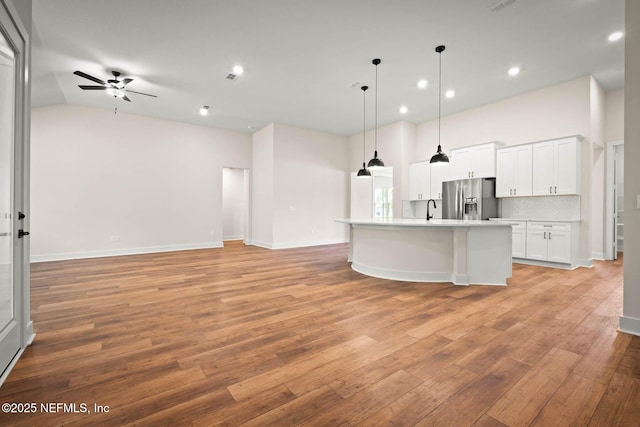 kitchen featuring light wood-style flooring, decorative backsplash, open floor plan, a sink, and stainless steel fridge with ice dispenser