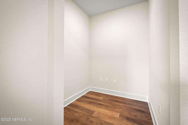 unfurnished room featuring baseboards and dark wood finished floors