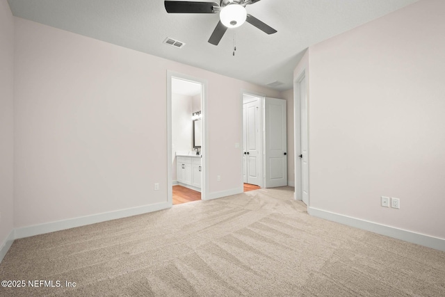 unfurnished bedroom with light carpet, baseboards, visible vents, ensuite bath, and ceiling fan