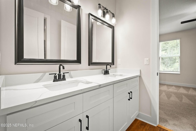 bathroom featuring double vanity, a sink, and baseboards