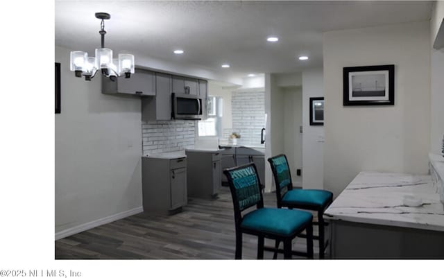 kitchen featuring decorative backsplash, stainless steel microwave, wood finished floors, gray cabinetry, and recessed lighting