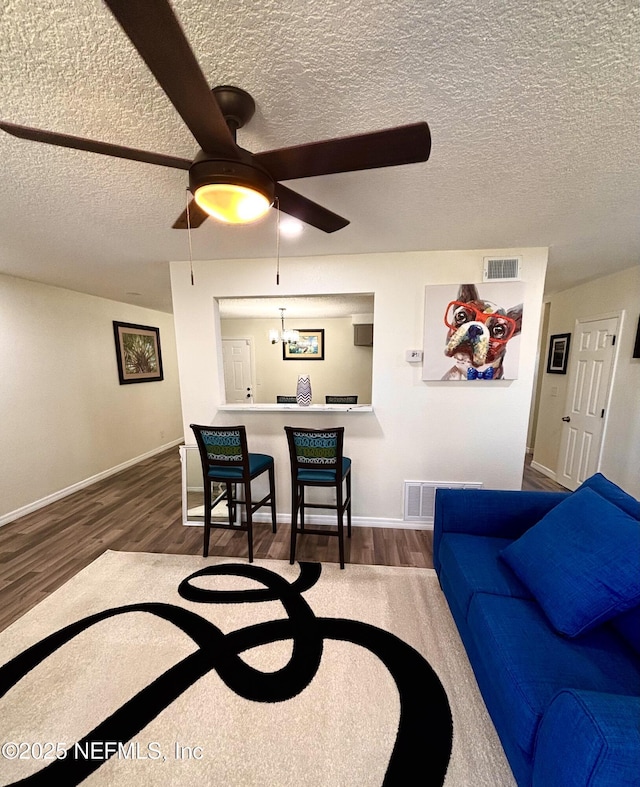 living area featuring a ceiling fan, baseboards, visible vents, and wood finished floors