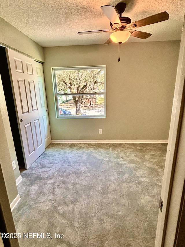 unfurnished bedroom featuring a textured ceiling, carpet, and baseboards