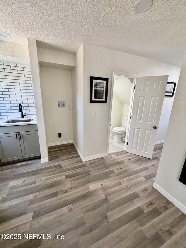 washroom featuring washer hookup, light wood-style flooring, a sink, laundry area, and baseboards